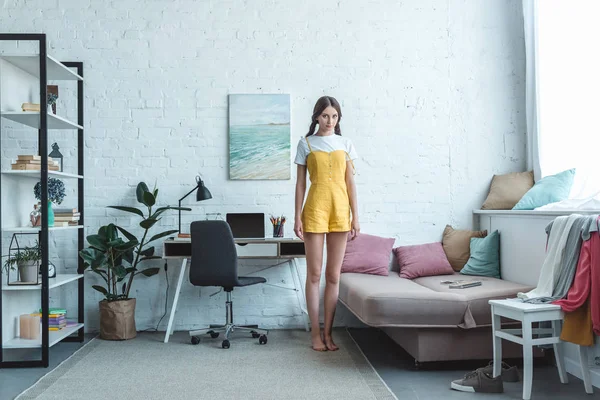 Schönes Teenager Mädchen Steht Wohnzimmer Mit Sofa Bücherregal Und Laptop — Stockfoto