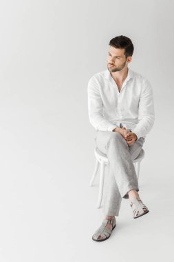 keten elbise gri arka plan üzerinde izole sandalye üzerinde oturan adam 