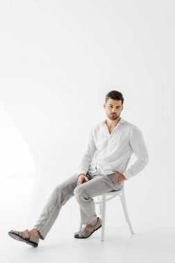 keten elbise gri arka plan üzerinde izole sandalye üzerinde oturan ciddi adam 