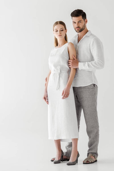 молодая пара в льняной одежде позирует изолированно на сером фоне
