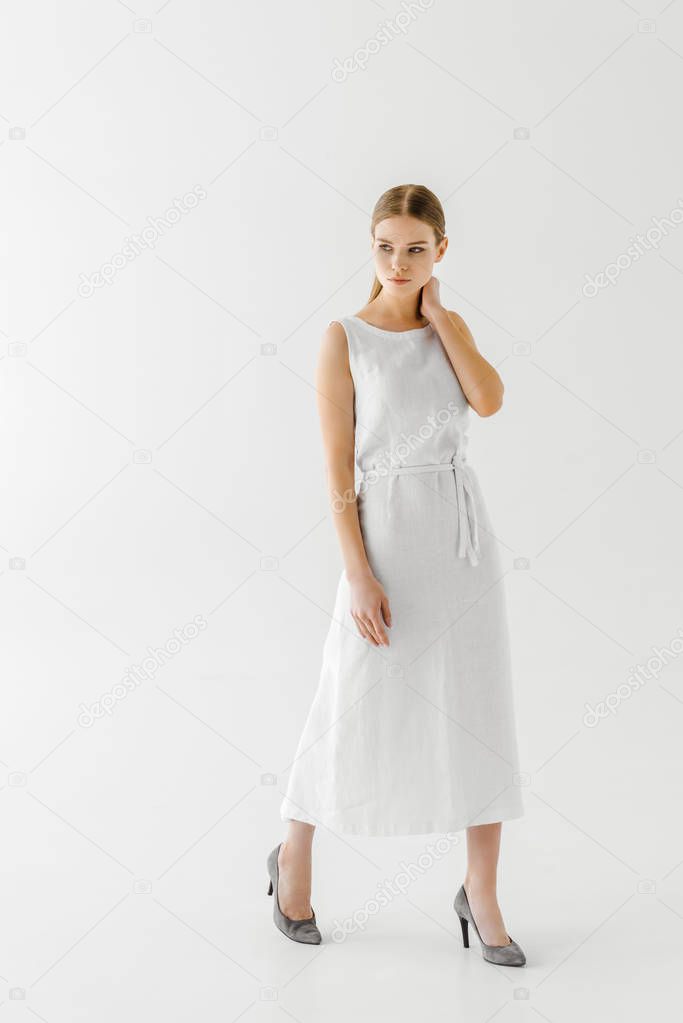 beautiful woman in linen white dress posing with hand on neck isolated on grey background 
