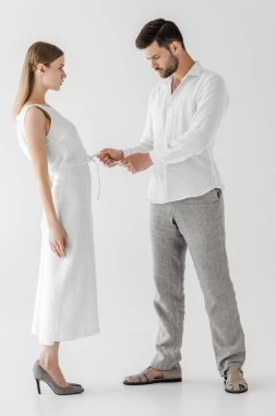 Erkek model çözmeyi beyaz keten elbise gri arka plan üzerinde izole kız arkadaşı yan görünüm 