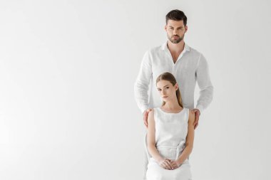 beautiful woman in linen white dress sitting on chair while her boyfriend standing behind isolated on grey background  clipart