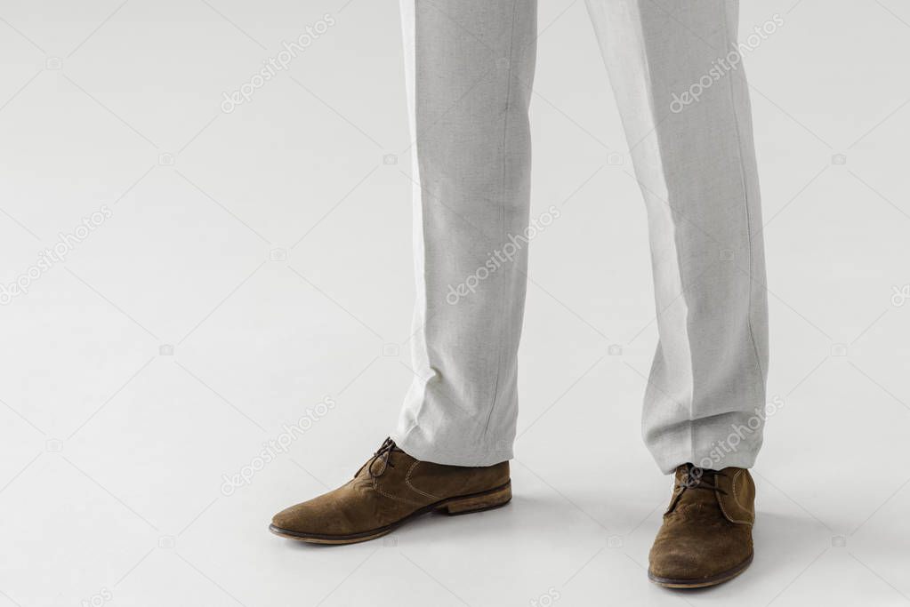 cropped image of male model in linen trousers and suede shoes isolated on grey background 