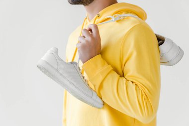gencin omuz üzerinde beyaz izole asılı beyaz spor ayakkabı ile sarı hoodie içinde kırpılmış atış