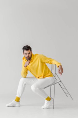 Beyaz koltukta oturan sarı hoodie çekici genç adam