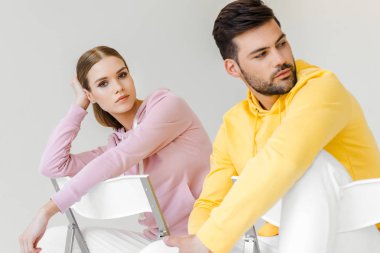 pembe ve sarı hoodies beyaz izole sandalyelere oturan genç erkek ve kadın modelleri