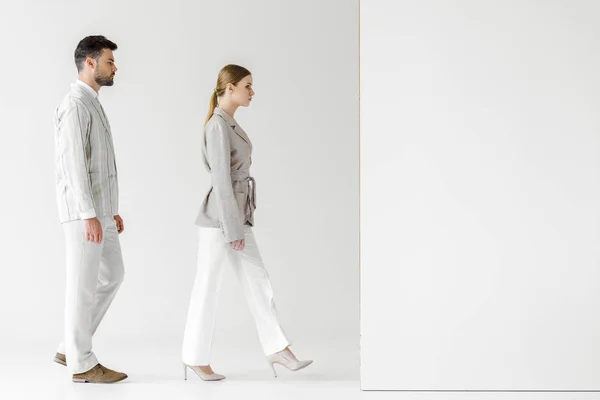 young male and female models in vintage clothes walking at white wall