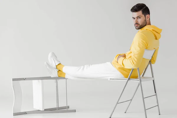 Jovem Bonito Com Capuz Amarelo Sentado Relaxado Branco Olhando Para — Fotografia de Stock