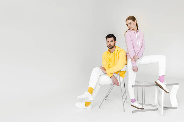 attractive young male and female models in colorful hoodies on white