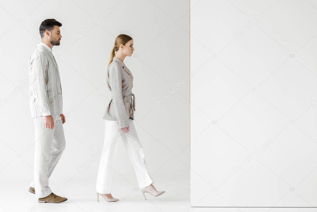 young male and female models in vintage clothes walking at white wall