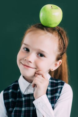 kameraya bakarak kafasına elma ile güzel küçük kızıl saçlı kız öğrenci portresi