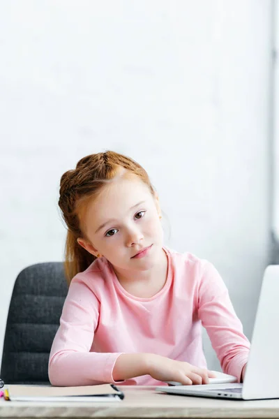 Gelangweilte Kleine Schülerin Schaut Auf Kamera Während Sie Hause Laptop — kostenloses Stockfoto