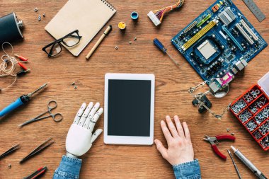 Dijital tablet araçlar tarafından çevrili ile masada robot el sittng ile elektronik mühendisinin resmini kırpılmış