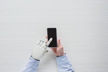 smartphone ile boş ekran ahşap masa üzerinde kullanarak cyborg el ile adamın resim kırpılmış 