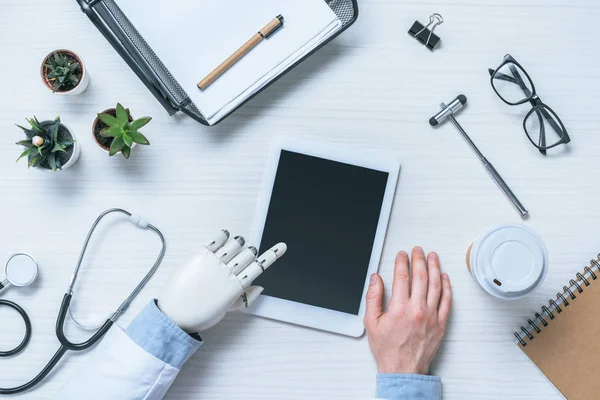 tıbbi araçlar ile masada boş ekran ile dijital tablet kullanarak protez kollu erkek doktor görüntü kırpılmış 