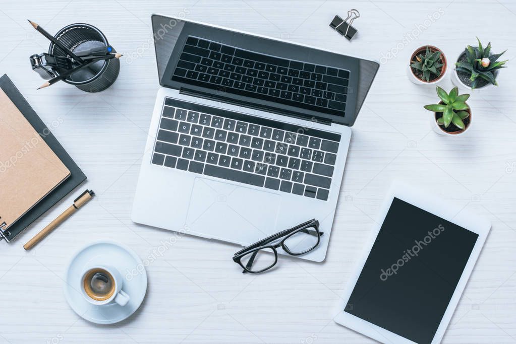 elevated view of businessman workplace with coffee cup, digital tablet and laptop on table