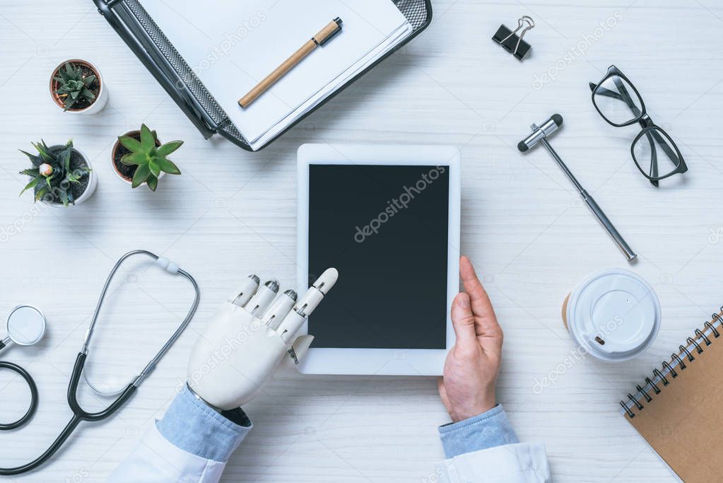 partial view of male doctor with prosthetic arm using digital tablet with blank screen 