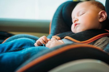 close-up portrait of adorable little baby sleeping in child safety seat in car