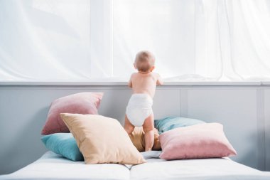 mutlu küçük bebek yatak yastık çok üzerinde duran ve pencereden bakarak bebek bezi