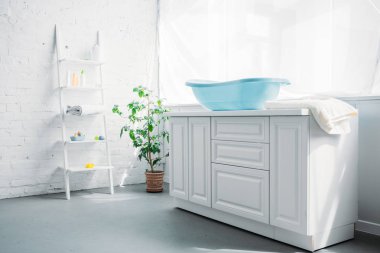 blue plastic childrens bathtub on stand in white modern room clipart