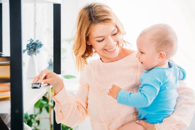 mutlu anne çocuk ve oyuncak arabası kitaplık üzerinde oynamaya