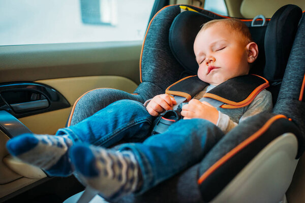 милый маленький ребенок спит в детском кресле безопасности в машине
