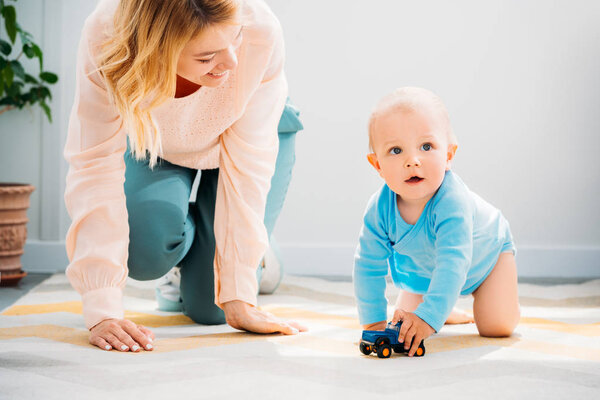 mother and child crawling together on carpet at home
