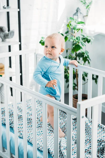 Entzückendes Kleines Baby Das Kinderbett Steht Und Wegschaut — Stockfoto