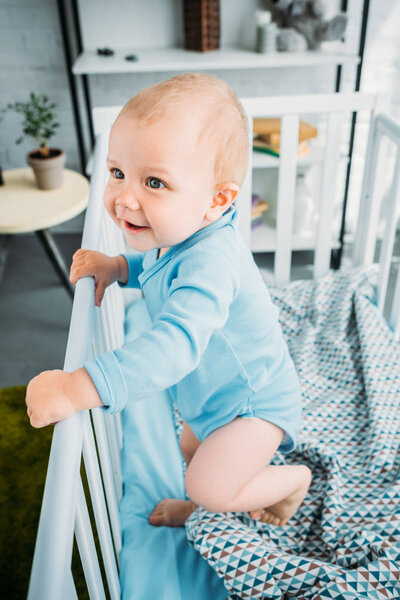 high angle view of happy little baby standing in crib