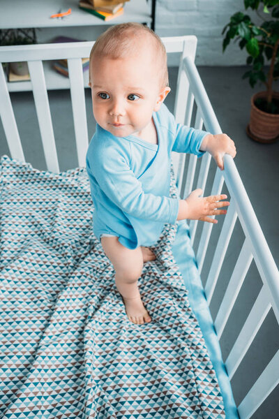 high angle view of cute little baby standing in crib