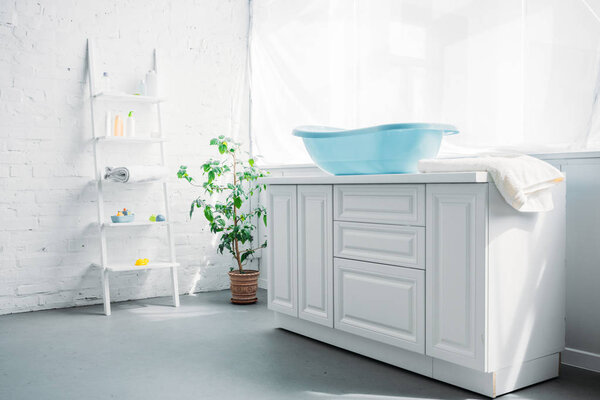 blue plastic childrens bathtub on stand in white modern room