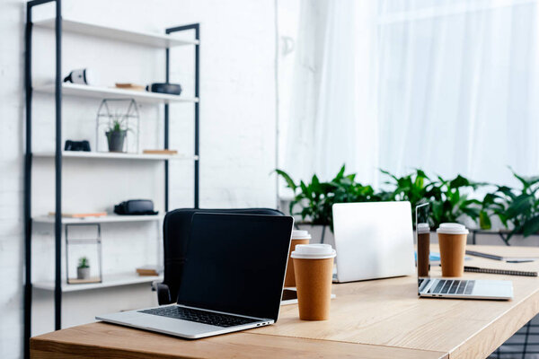 laptops and paper cups on table in modern office