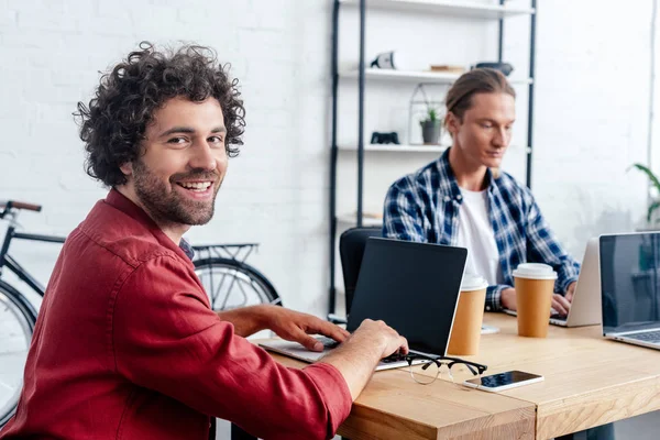 Joven Usando Ordenador Portátil Con Pantalla Blanco Sonriendo Cámara Mientras —  Fotos de Stock