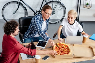 İşyerinde pizza yemek genç arkadaşları gülümseyerek, yüksek açılı görünüş 