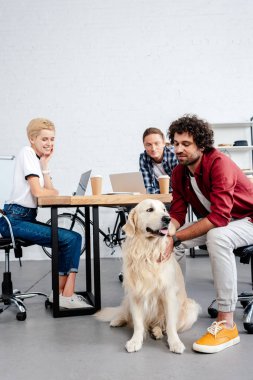 ofiste çalışırken köpeğe arıyorum Genç iş arkadaşları gülümseyerek 