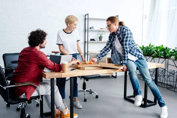 Jóvenes Compañeros Trabajo Comiendo Pizza Juntos Mientras Trabajan Juntos Oficina —  Fotos de Stock