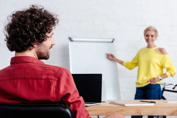 Vista Trasera Joven Sonriente Mirando Una Colega Apuntando Una Pizarra — Foto de stock gratis