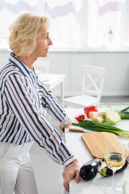 mutfak pişirme sırasında mutfak tezgahına eğilerek çekici gri saç kadın yan görünüm 