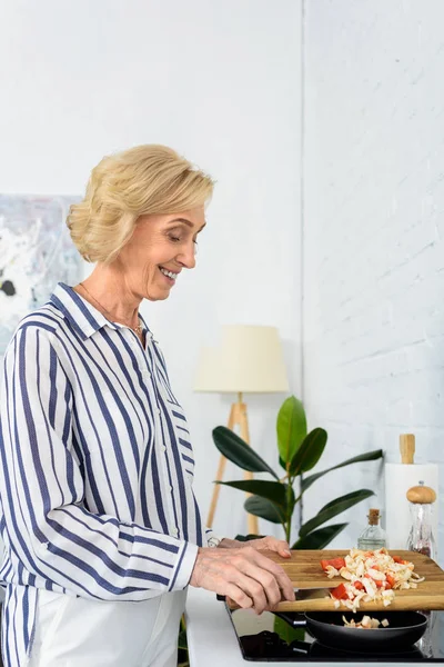 Side View Smiling Grey Hair Woman Putting Vegetables Frying Pan — Free Stock Photo