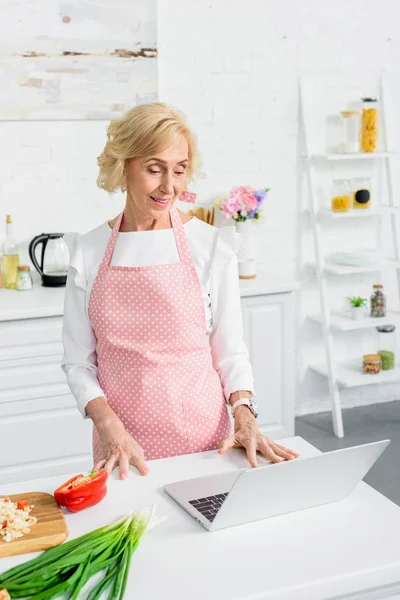 Attraktive Seniorin Nutzt Laptop Zum Kochen Küche — kostenloses Stockfoto