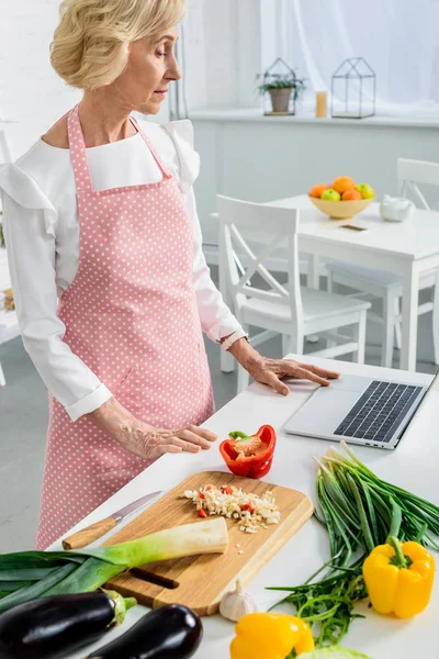 Beautiful Senior Woman Using Laptop Cooking Kitchen — Free Stock Photo