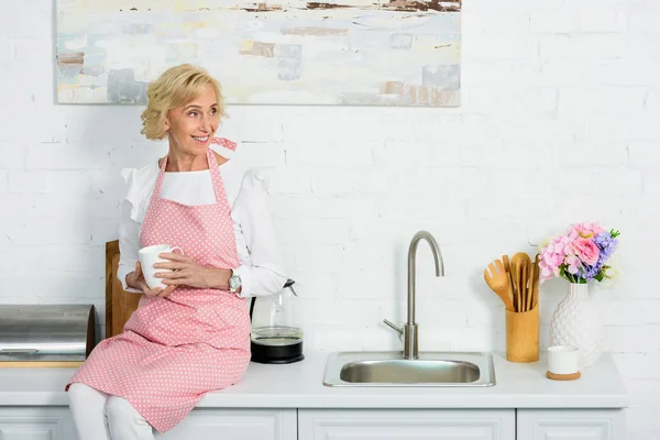 Atractiva Mujer Mayor Sentada Mostrador Cocina Con Taza Café Mirando — Foto de stock gratuita