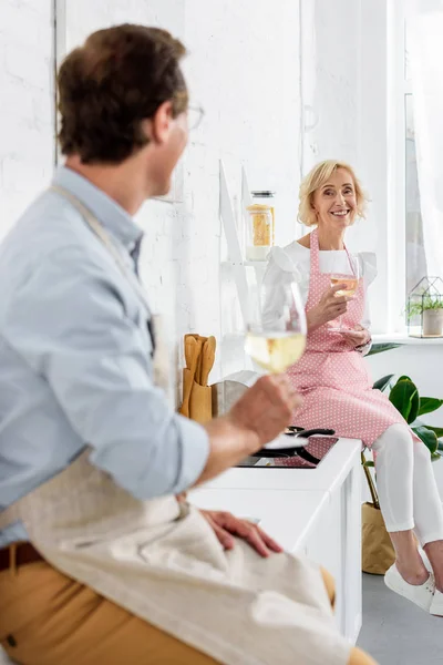 幸せな先輩カップルのワインのグラスを持って 一緒に料理をしながらカメラで笑顔  — 無料ストックフォト