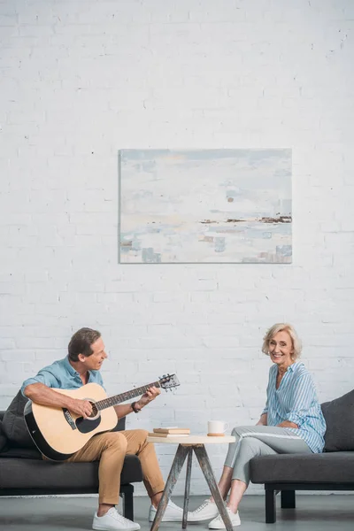 Homem Feliz Tocando Guitarra Acústica Olhando Para Esposa Sênior Sorrindo — Fotos gratuitas