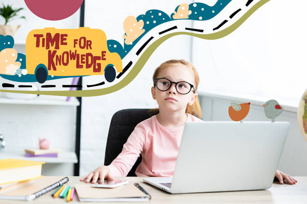 Thoughtful little schoolchild in eyeglasses looking up while sitting at desk and using laptop with "time for knowledge" lettering