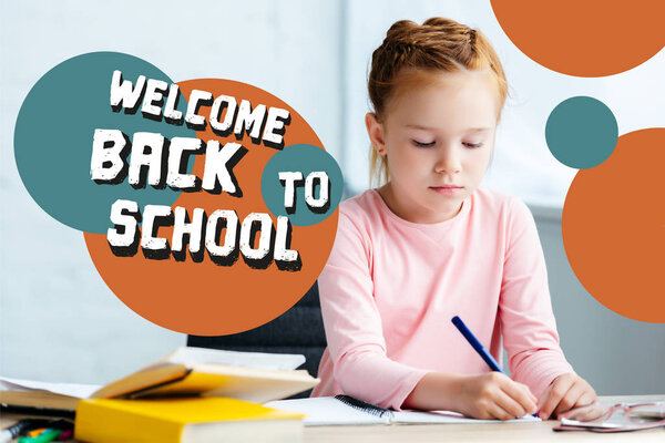 adorable red haired schoolgirl sitting at desk and studying at home with "welcome back to school" lettering