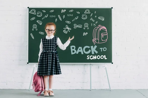 Adorable Colegiala Con Mochila Mostrando Pizarra Con Iconos Letras Vuelta — Foto de Stock