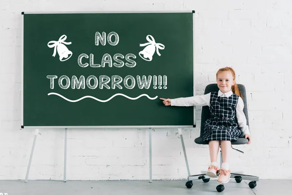 Adorable Little Schoolgirl Smiling Camera Pointing Chalkboard Class Tomorrow Lettering — Stock Photo, Image