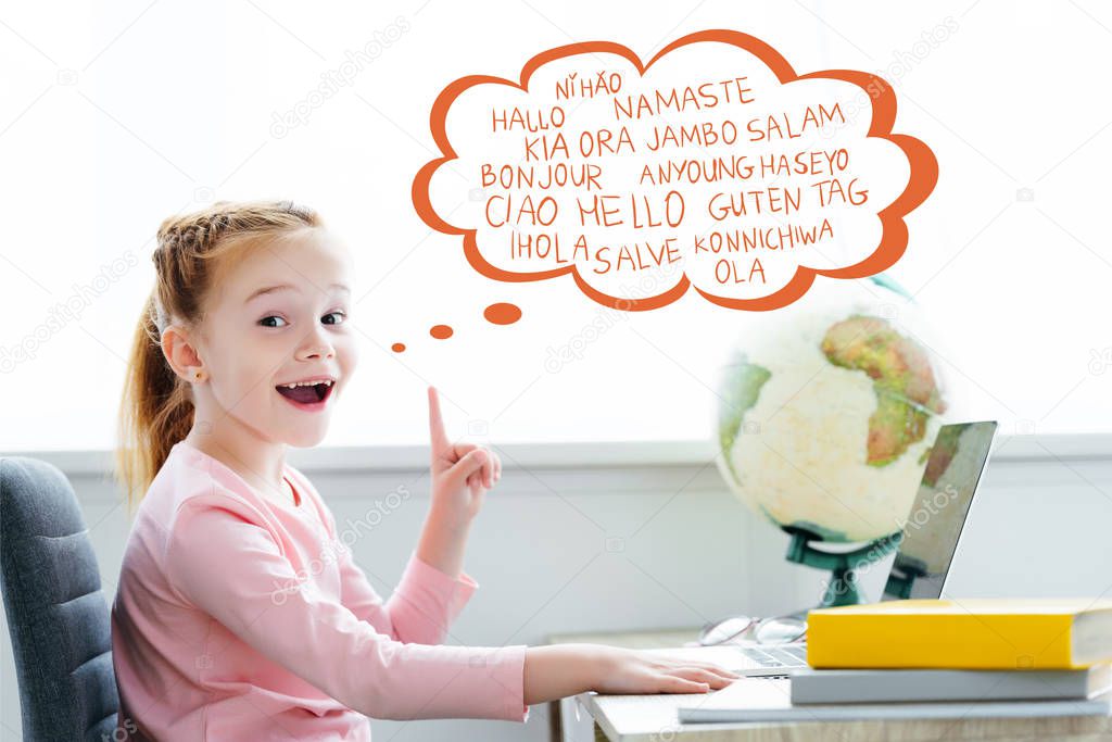redhead schoolchild studying with books and laptop and pointing up on words on different languages in speech bubble 
